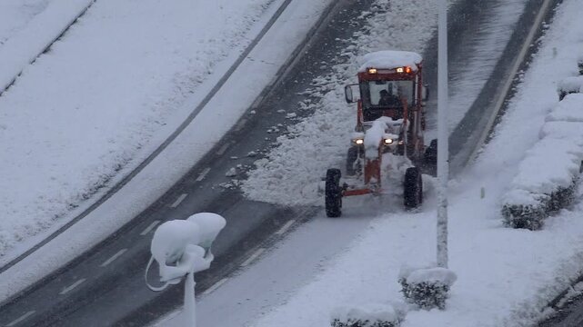 Snow removal vehicles clear a highway road during heavy winter weather and blizzard conditions.