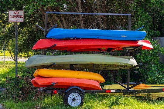 Colorful kayaks stacked on storage rack near trees