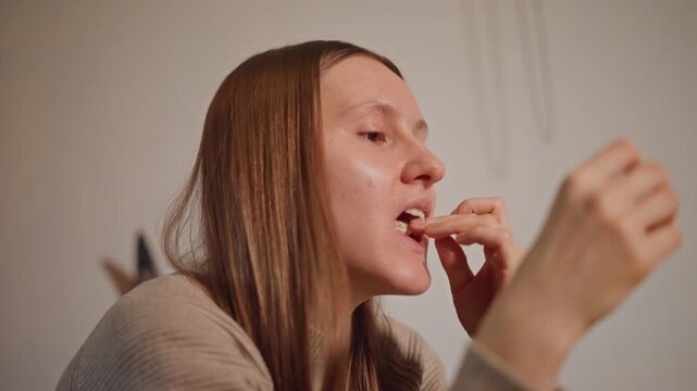 Person delicately removing tangerine skin inside. Woman gently peeling tangerine at table under gentle light. Young woman carefully separates tangerine segments while seated comfortably indoors