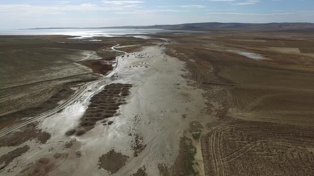 Aerial view shows flood sediment and soil deposits spread across a muddy flood plain surface.