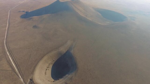 Aerial view of volcanic tuff ring cone crater and a barren geological sinkhole depression formation.