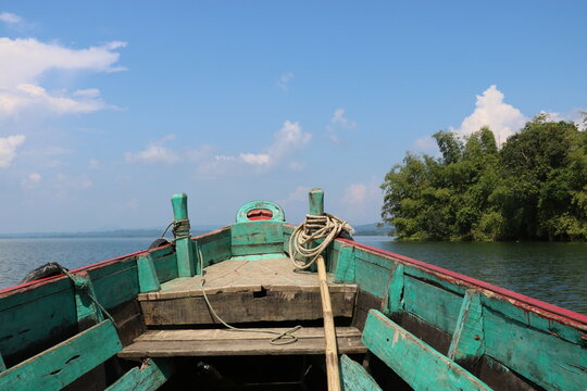 Weathered green wooden boat floating calmly on clear blue water during a bright sunny summer day