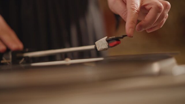 Closeup hand placing stylus on vinyl, warm analog lighting, intimate home audiophile ritual, careful cueing on platter with visible grooves and tactile detail, slow deliberate motion