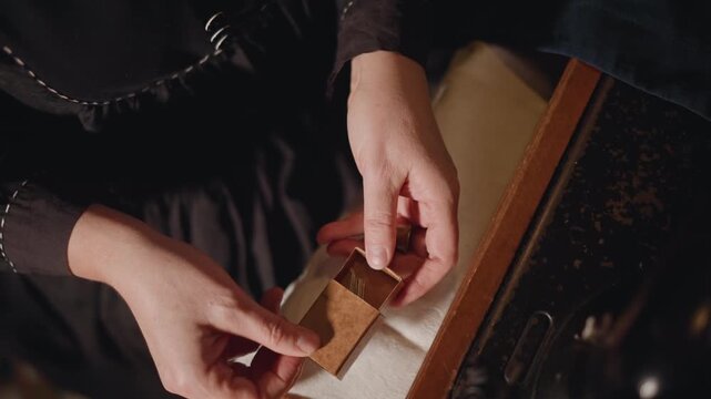 Closeup hands opening tiny wooden box, seamstress carefully inspecting brass latch and velvet lining on aged suitcase, warm lamp light, nostalgic atmosphere, slow deliberate motions of a patient maker