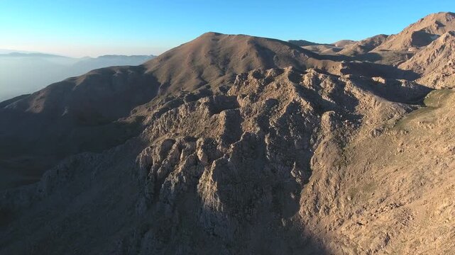 Aerial view of treeless rocky slopes across the Zagros Mountains in Iran across rugged terrain.