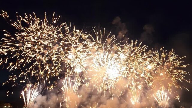 Stunning fireworks display lighting up the night sky with multiple golden bursts and smoke trails