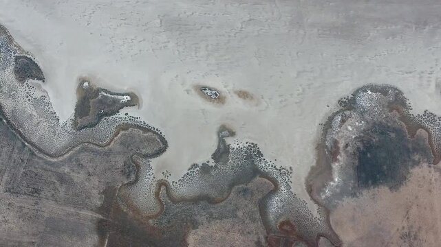 Aerial view shows Aral Sea salt flats in Uzbekistan with barren shoreline and dry lakebed.