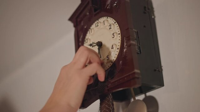 White hand winds antique clock face with precise movement, closeup on dial and knob, wood grain and aged patina highlighted under soft light, meticulous action evoking care and timing