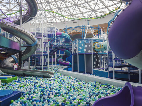 Indoor playground filled with colorful balls, slides, tunnels, climbing structures, soft play equipment, bright interior, family recreation, active children, entertainment, leisure concept