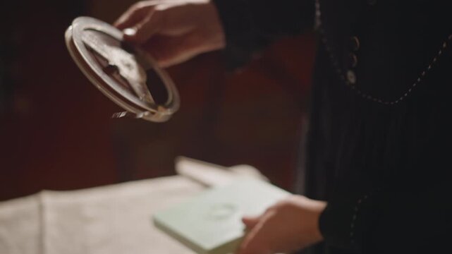 Precise movie tape loading process. Vintage hands carefully thread and align film. Detailed view of fingers meticulously installing and threading film reel under moody theater lighting