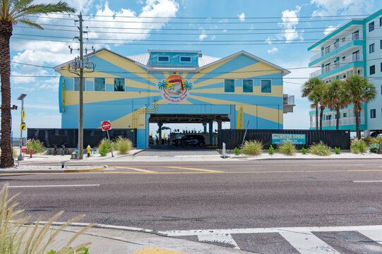 A colorful beachfront Caddy's Madeira Beach restaurant on stilts sits across a sunny coastal street. Editorial Use Only August 6, 2026 MADEIRA BEACH, FL USA with palm trees, shaded parking and ocean v