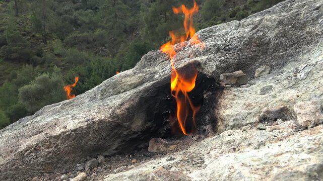 Flame of burning methane gas emerging from underground rock crack in geological formation.