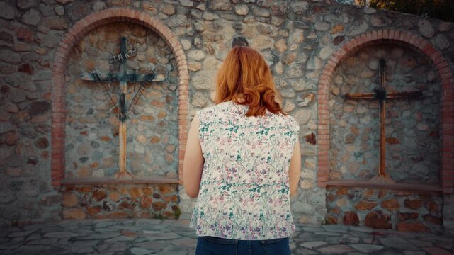 Woman prays at outdoor religious crucifix to end wars in the world