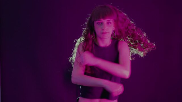 Passionate woman dancing in a nightclub under purple neon light