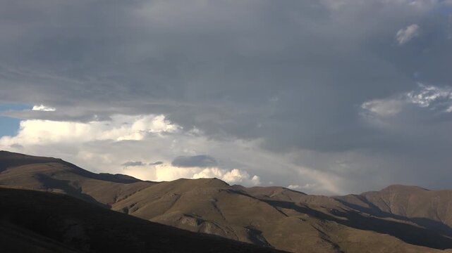 Cloud movement drifts over treeless arid Zagros mountains near Shiraz Iran, revealing barren hills.