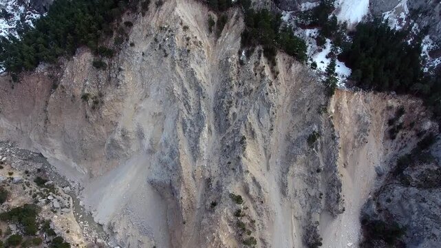 Aerial view of massive landslide tearing through forested mountain slope and exposed rock layers.