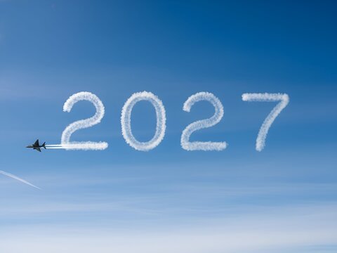 The number 2027 written in clouds behind a plane flying over a city at sunset, future travel goals, urban progress