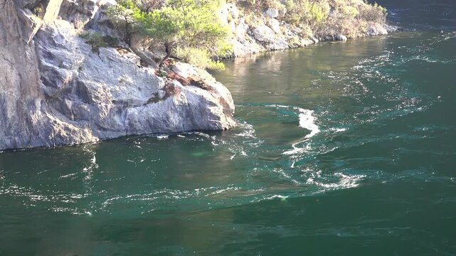 Rotational vortex motion forms a visible whirlpool on flowing river water surface.