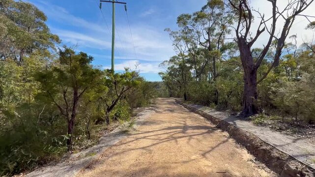 Footage of walking down a remote dirt track fire trail while exploring the surrounding wilderness in the Blue Mountains National Park in New South Wales, Australia