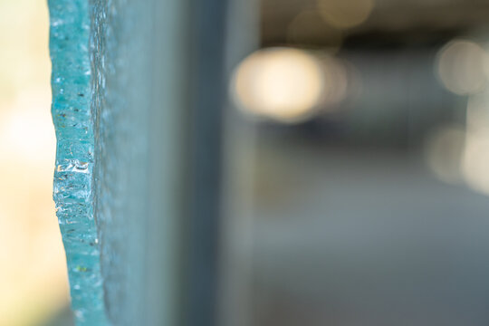Broken tempered glass window with chipped detail and blurred background.