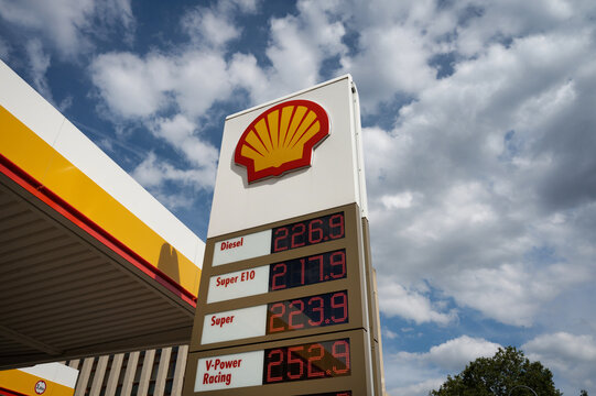 Cologne, Germany August 07 2026: Digital price board at a Shell gas station showing high fuel prices for diesel and petrol against a cloudy blue summer sky in Germany.