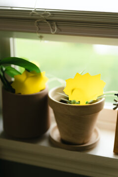 Yellow sticky traps placed in potted houseplants on a windowsill to catch fungus gnats
