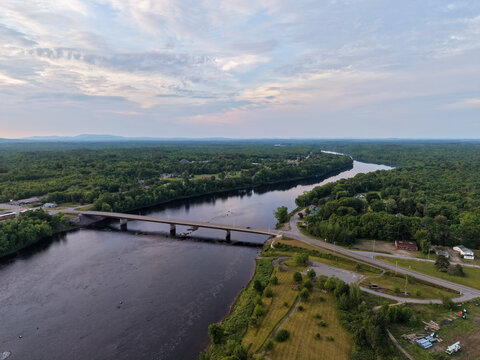 Aerial View Of Bridge Crossing the Penobscot River in Howland, Maine with Forested Countryside At Dawn With Road And Horizon