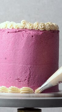 Piping buttercream border on a pink cake, process of decorating a pink cake with cream buttercream piping, process of decorating a pink vintage style cake