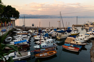 Fototapeta premium Marina in Lovran, Croatia with docked boats near stone piers and calm coastal water