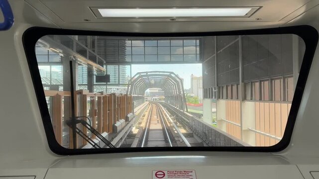 First person point of view of a light rail train driving on elevated tracks in the city.