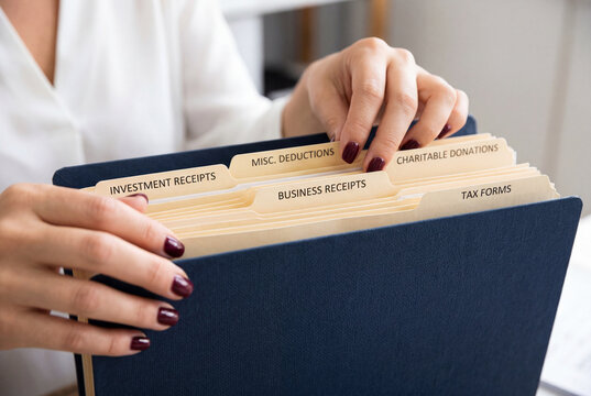 Woman organizing paperwork in a dark blue accordion file folder with labeled receipt tabs