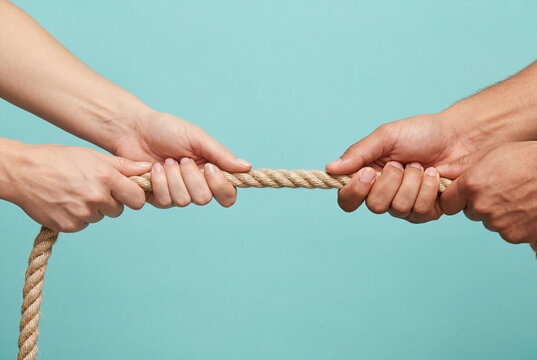 Two pairs of hands pulling a thick rope in a tug of war