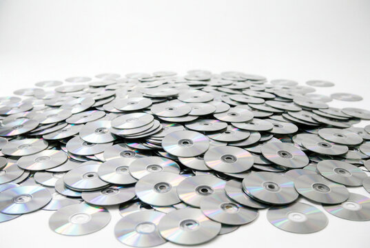 Haphazard pile of reflective silver discs on white surface