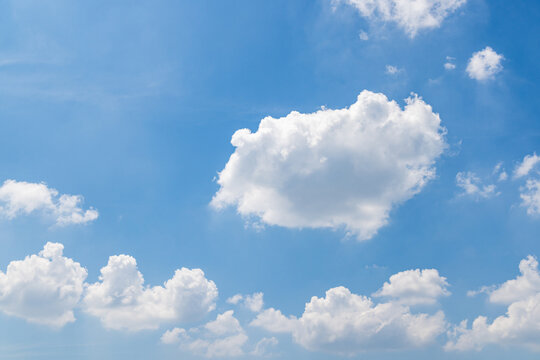 Bright blue sky dotted with fluffy white cumulus clouds, forming a calm natural daytime scene.