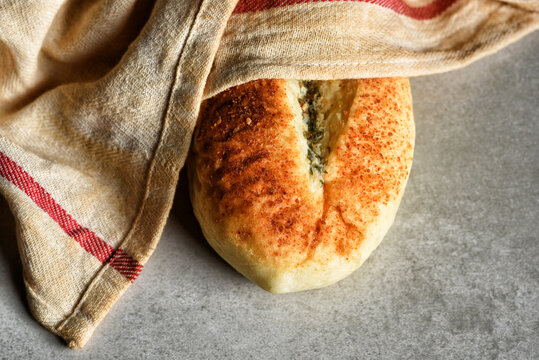 Artisan Bread Still Life. A fresh baked loaf of Garlic and Basil flavored bread under a towel.