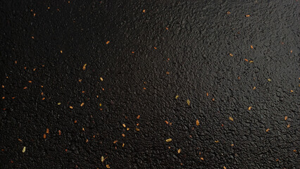 Top down view of wet dark asphalt street texture with scattered tiny dry autumn leaves background. © Jassem