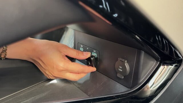 a hand plugging a wireless CarPlay adapter into a car USB port beside a 12V socket, demonstrating cable-free smartphone integration and infotainment connectivity.