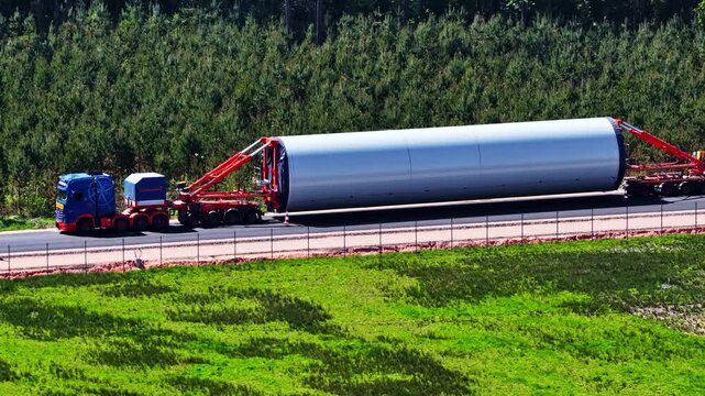Heavy duty truck hauling an oversized wind turbine tower section for a wind farm construction
