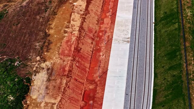 Top-down aerial perspective flying over a railroad track under construction next to red earth