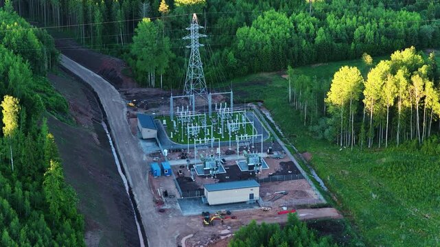 Aerial view of a new electrical substation with a power line tower in a remote wooded area