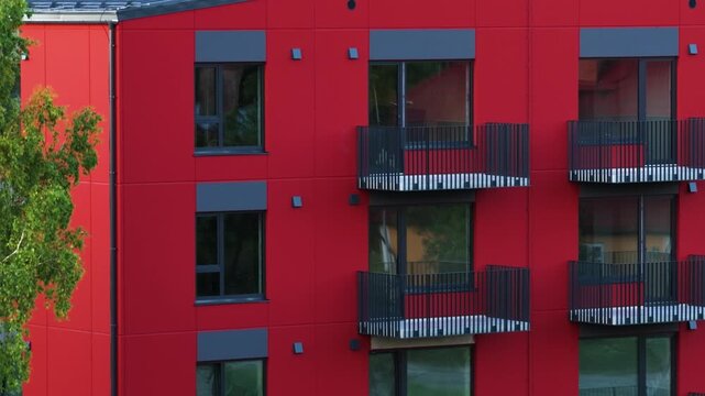 Red modern apartment building facade with balconies at a construction site