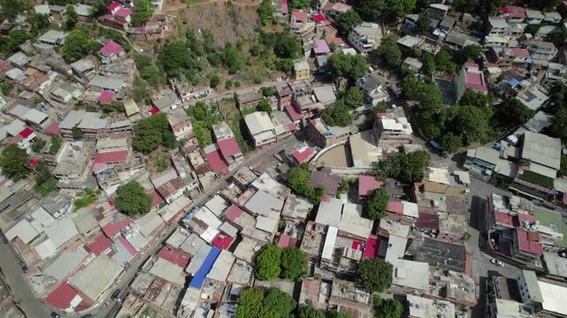 drone shot tilt up revealing expansive humble residential settlement built into a steep valley slope in La Guaira overlooking Venezuelan coastline.