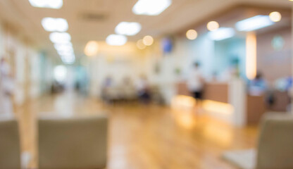 Obraz premium Blurred image of a modern hospital reception area with soft lighting, featuring waiting chairs and people in the background, creating a calm atmosphere.