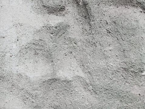 Rough grey concrete wall texture background with grainy surface structure and subtle shadows, perfect for industrial design backdrop or abstract textured pattern.