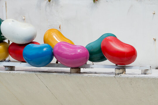 colorful bean-shaped glossy outdoor art sculptures featuring vibrant red, blue, pink, yellow, and green painted smooth kidney bean shapes