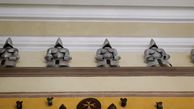 row of morion helmets palace armoury grand master's palace valletta steel helmets mounted display wall maltese cross emblem knights history malta historic government building military artifacts