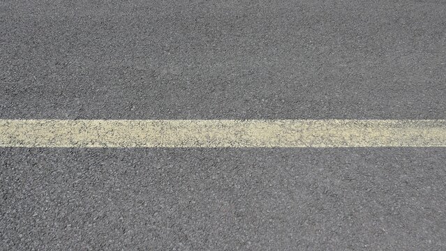 Close Up of Worn Yellow Center Line on Asphalt Road