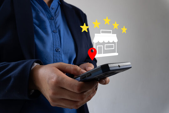 Person holds smartphone. Golden stars float above a store icon. Red pin marks location on digital map. User appears engaged, possibly rating or reviewing