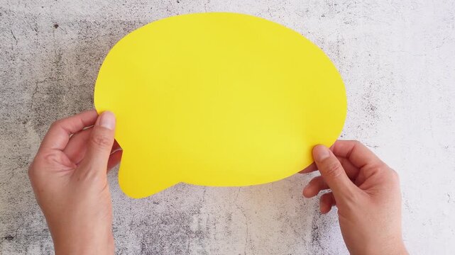 Yellow speech bubble held by two hands