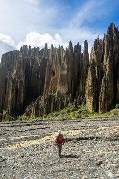 Woman with red poncho walking toward the Valle de las Animas spires near La Paz, Bolivia